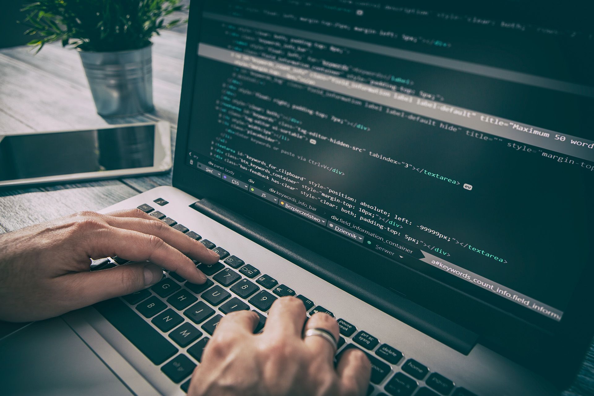 Ein Laptop und zwei Männerhände in Nahaufnahme mit HTML Code auf dem Bildschirm